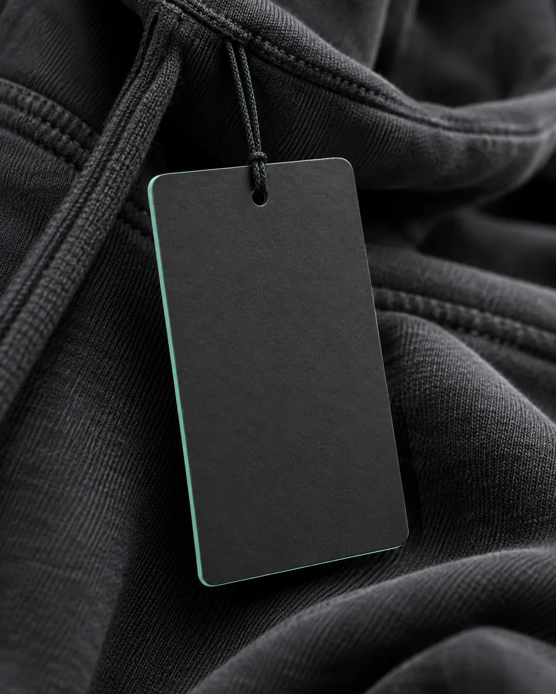 Concept: a black hangtag with a mint edge hanging on a charcoal hoodie drawcord