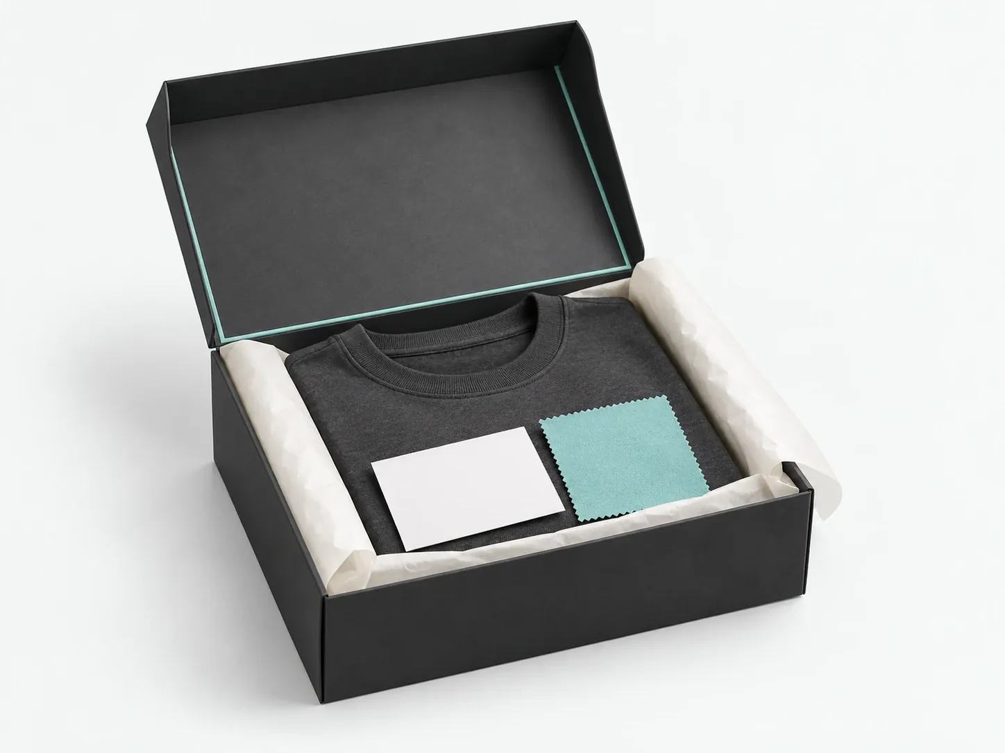 Concept packaging: an open black box with a mint inner edge holding a folded charcoal tee and fabric swatch cards