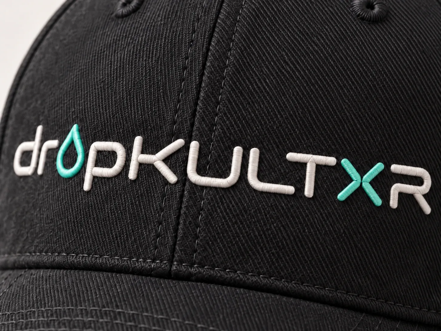 Close detail of the flat bone and mint dropKULTXR embroidery on black twill